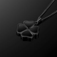 A black four-petal clover pendant necklace on a matching black chain, displayed against a dark reflective background.