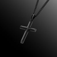 Black cross pendant on a chain against a dark background