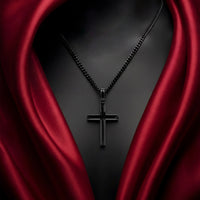 Black cross necklace on a dark background with red fabric