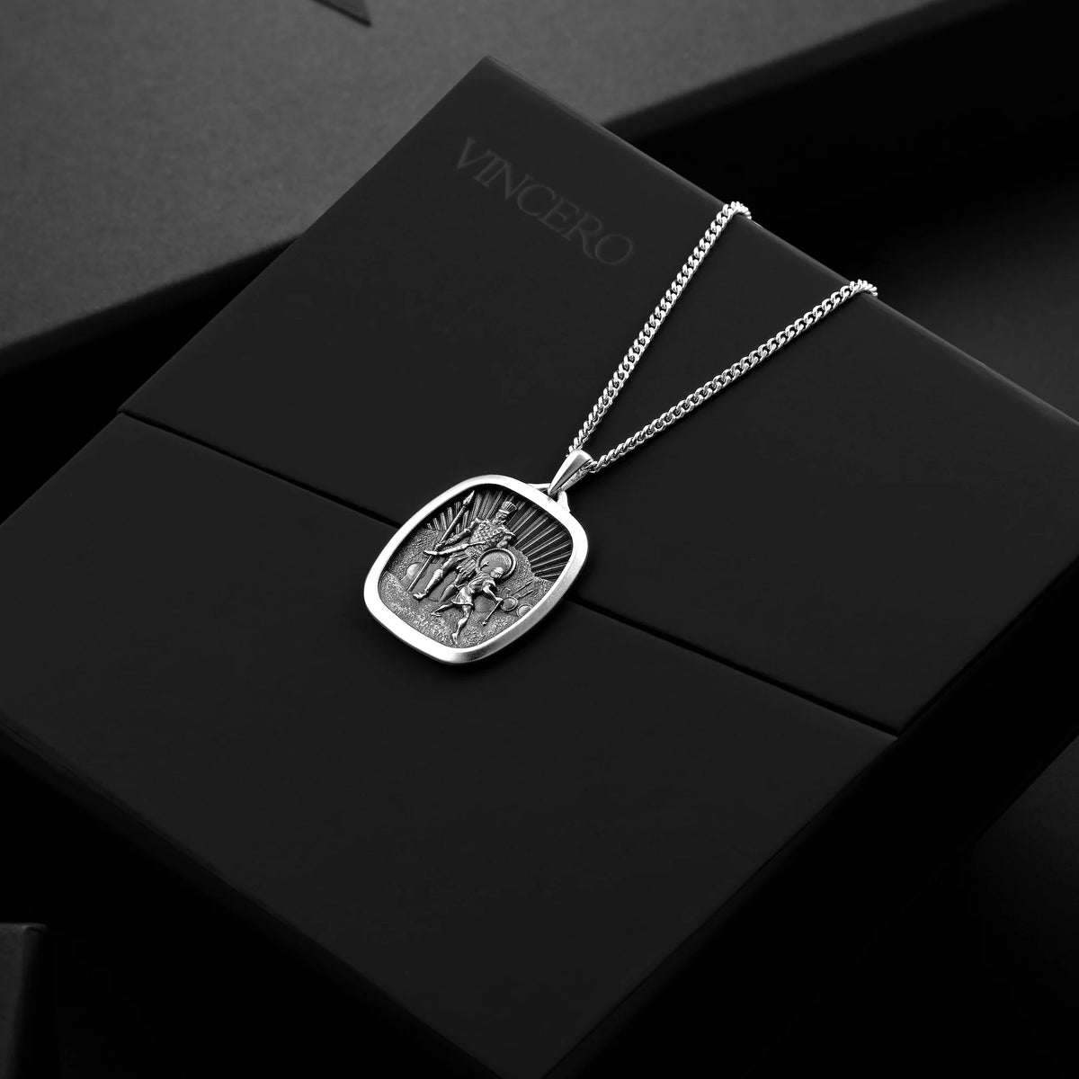 Silver necklace with a pendant on a black box with 'Vincero' branding.
