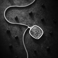 Silver pendant necklace on a dark textured surface