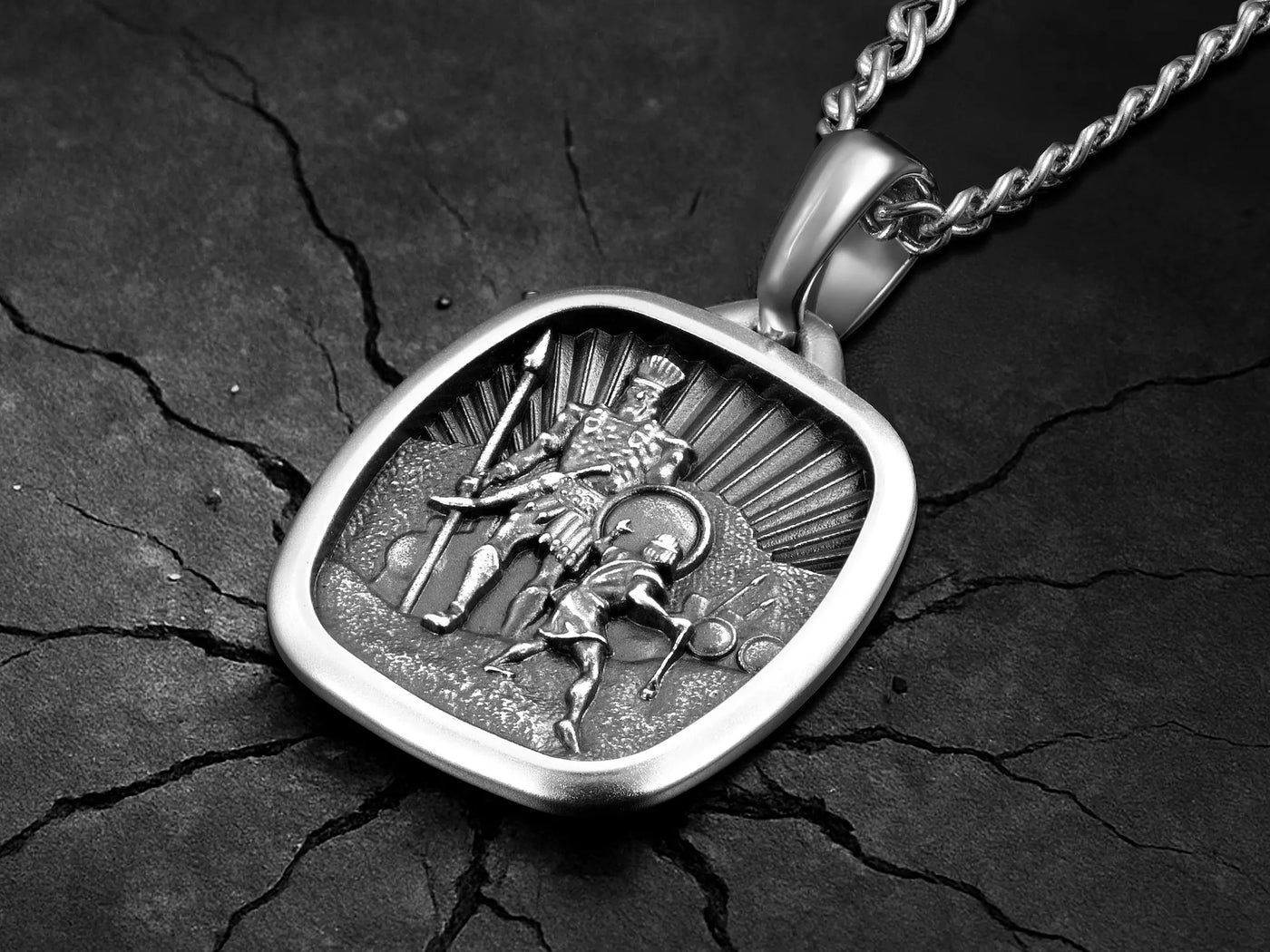 Silver pendant with a detailed design on a dark, textured surface