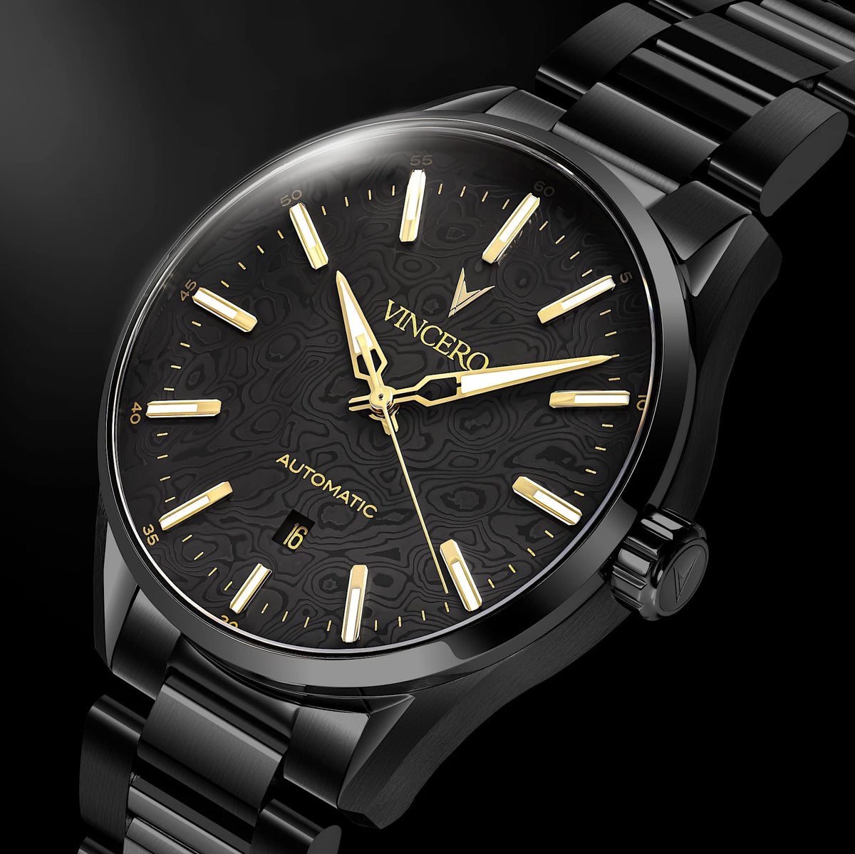 A close-up of a VINCERO automatic watch with a black textured dial, gold-tone hands and indices, and a black metal link bracelet, set against a dark background.