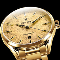 Gold-tone automatic watch with a textured wood-grain dial and matching gold bracelet, shown in a close-up studio shot against a black background.