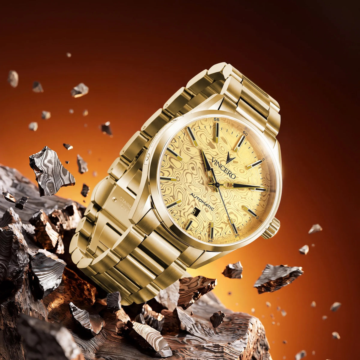 A gold-tone stainless steel wristwatch with a patterned gold dial and matching gold bracelet, shown at an angle amidst floating metallic fragments on a dark brown and orange gradient background.