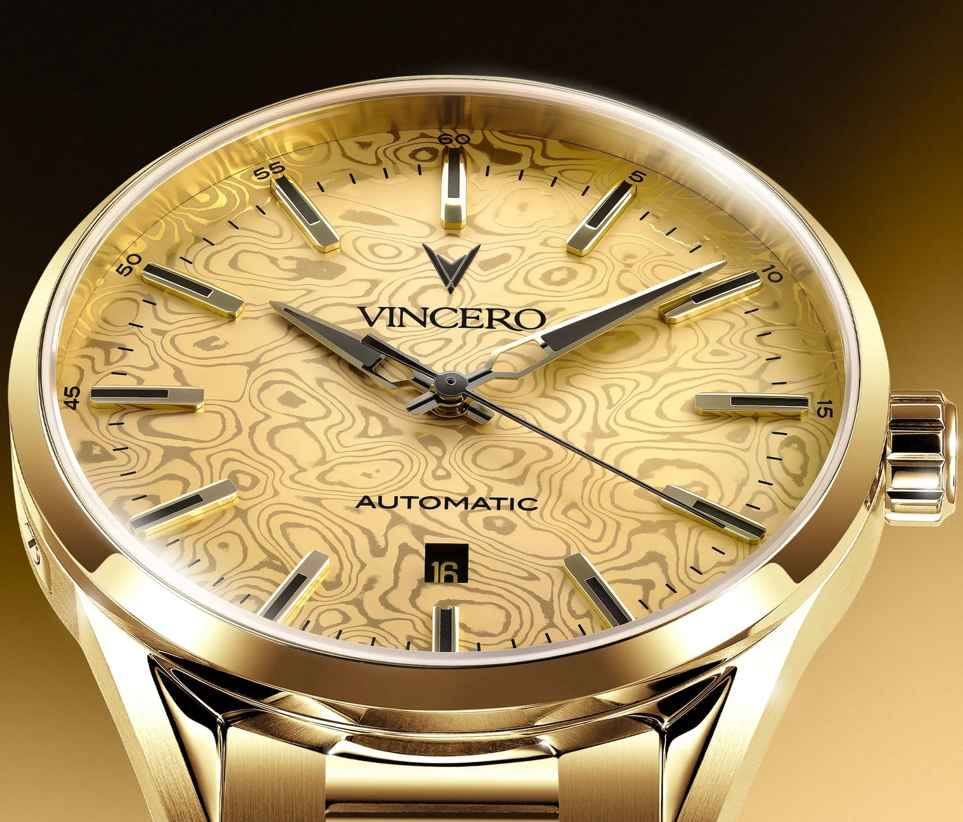 A close-up of a gold-tone Vincero automatic wristwatch with a patterned gold dial and matching metal bracelet, shown against a dark gradient background.