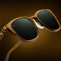 Gold-framed sunglasses with black lenses on a brown background
