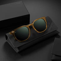 Gold-framed sunglasses with dark lenses on a black background
