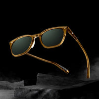 Gold-framed sunglasses with dark lenses on a black background