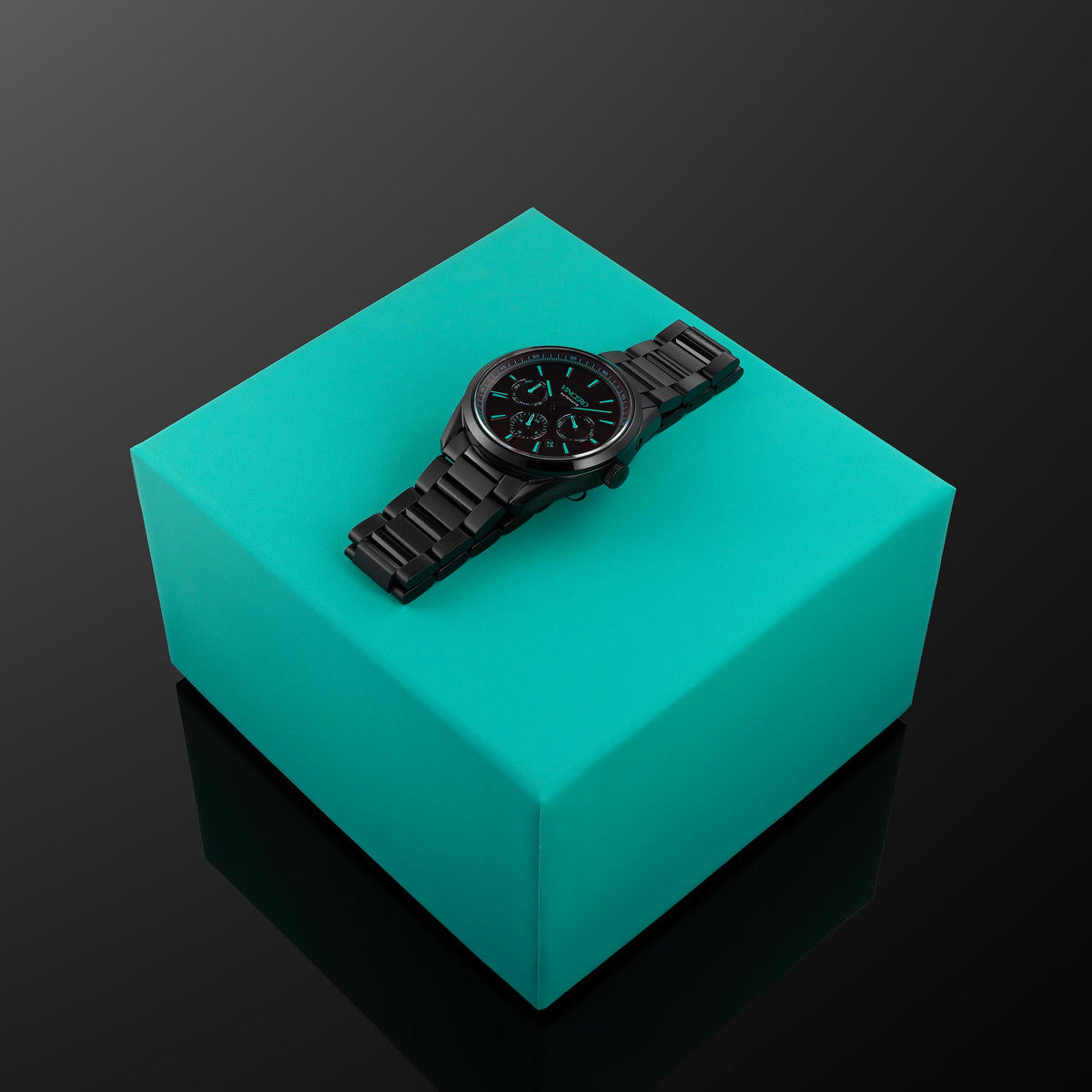 Black wristwatch with green glowing face on a green box for men