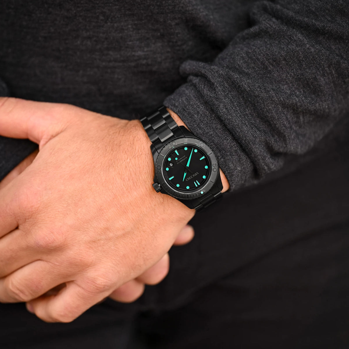 Person wearing a black wristwatch with a dark background