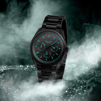 Black wristwatch with green accents on a dark, smoky background