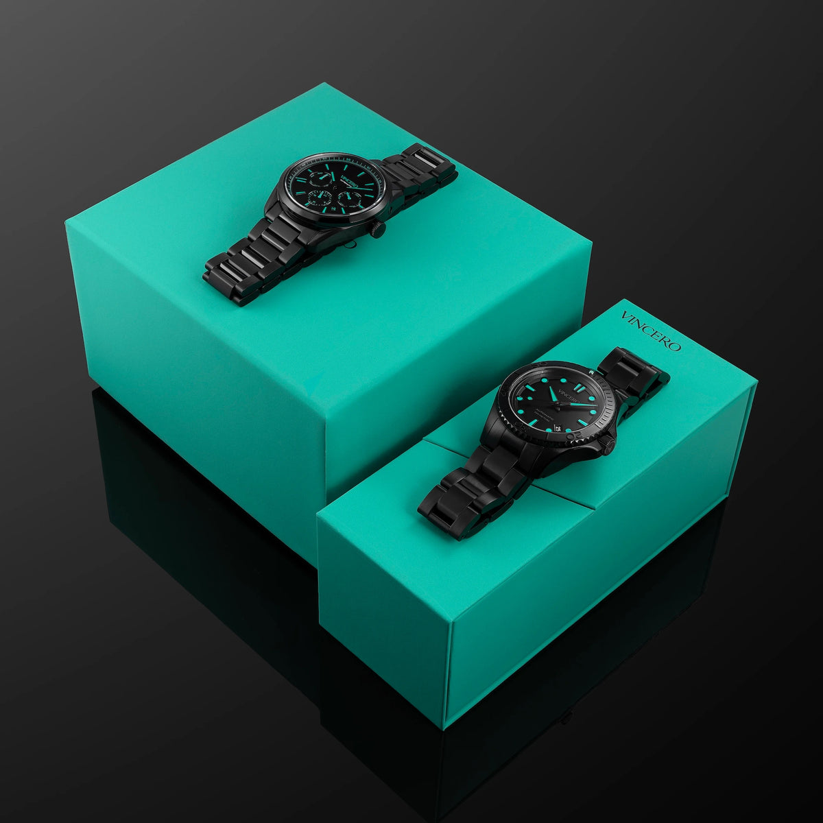 Two black watches on turquoise boxes against a dark background