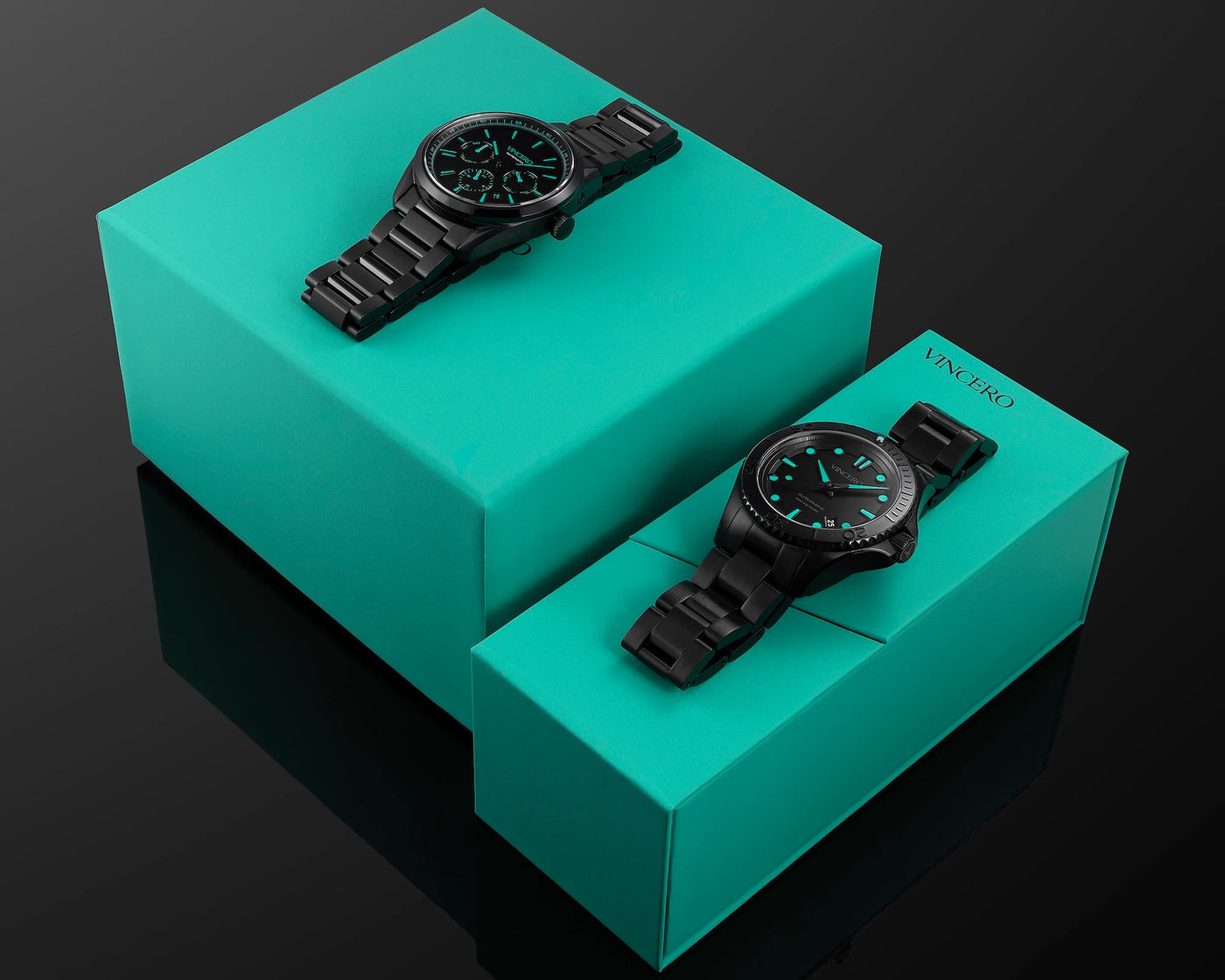 Two black watches on turquoise boxes with a dark background