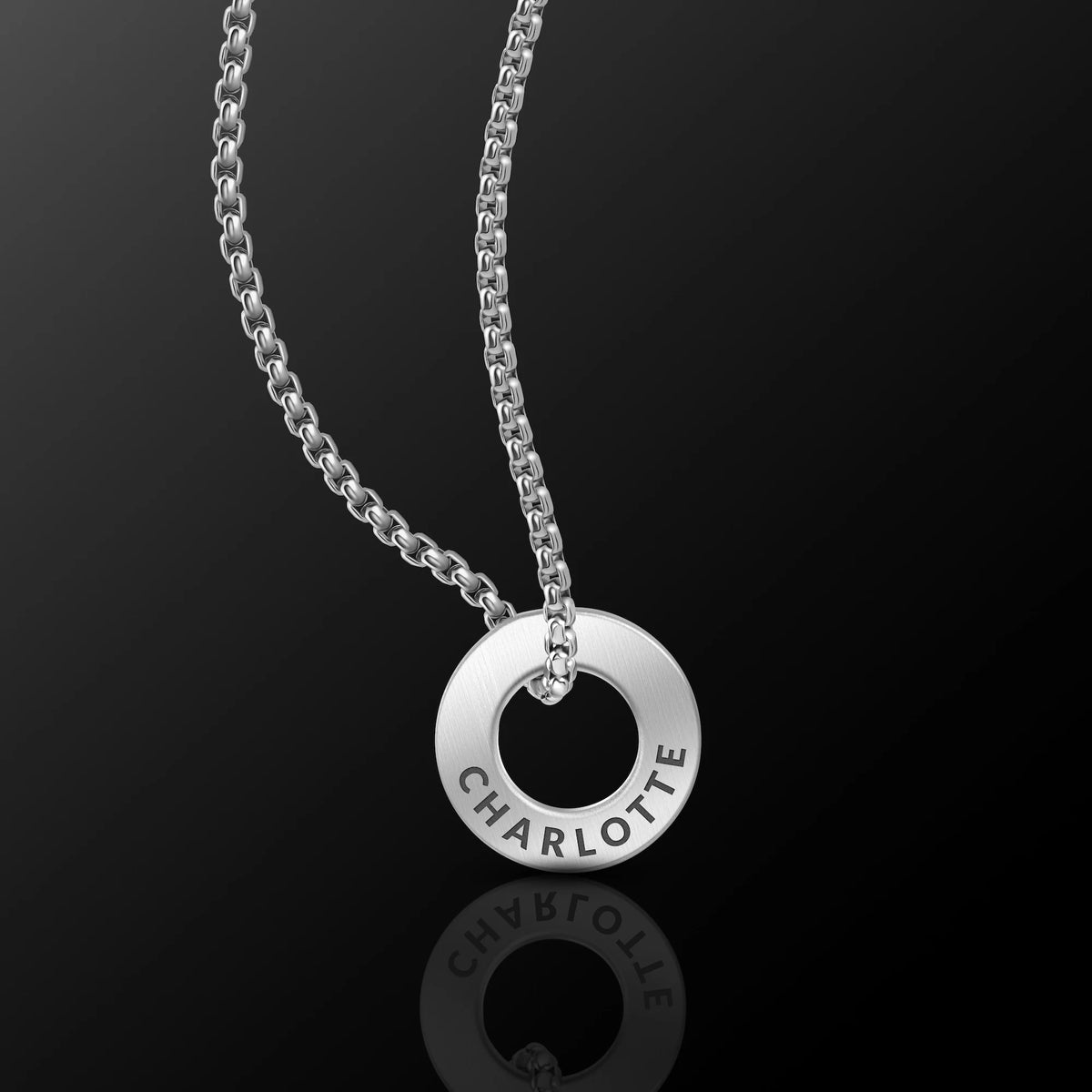 Silver necklace with a round pendant on a black background