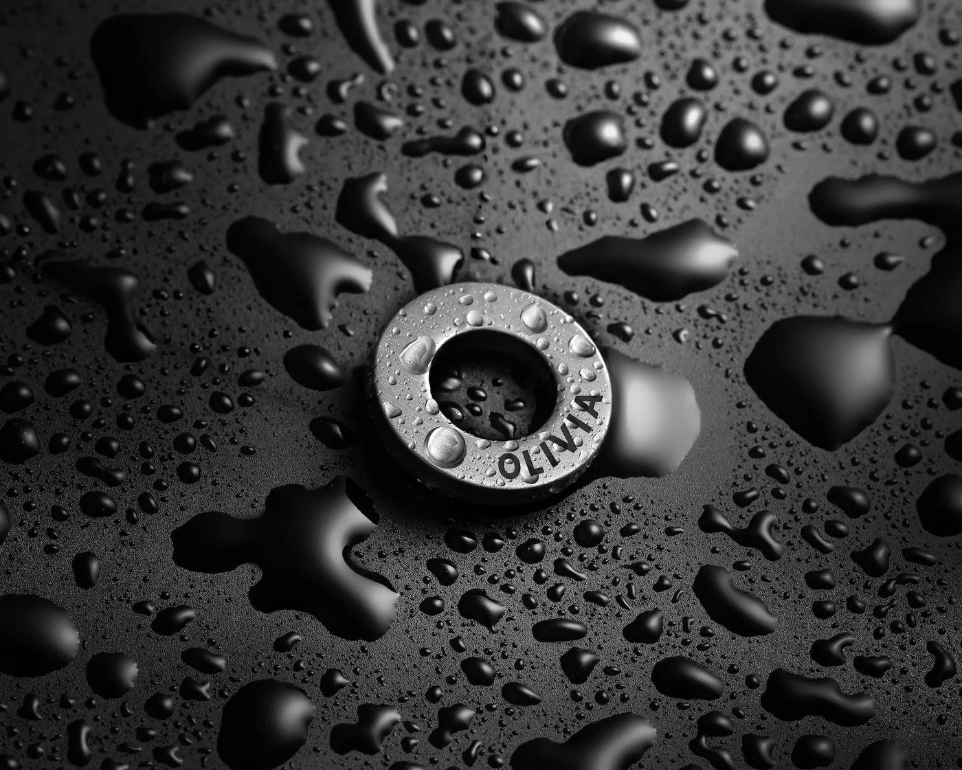Metallic washer with 'MAX' branding on a black surface with water droplets