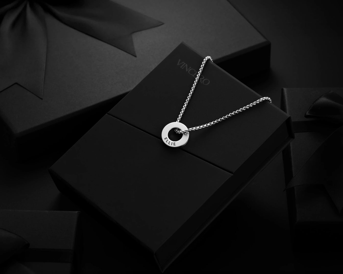 Silver necklace with a circular pendant on a black box
