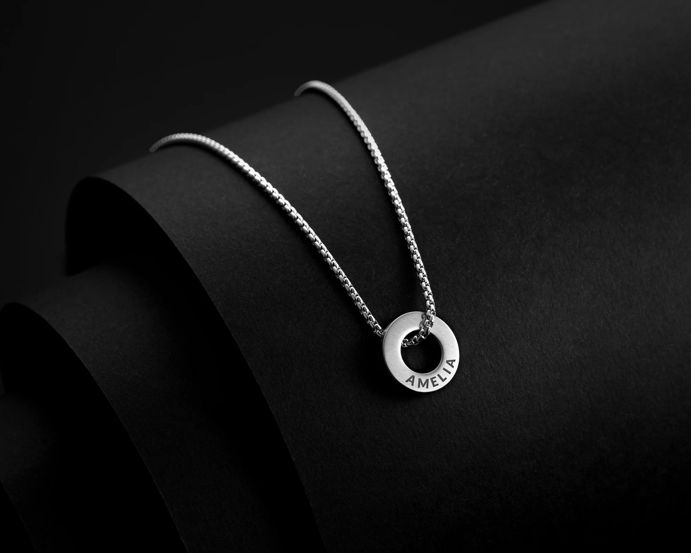 Silver necklace with a pendant on a black background