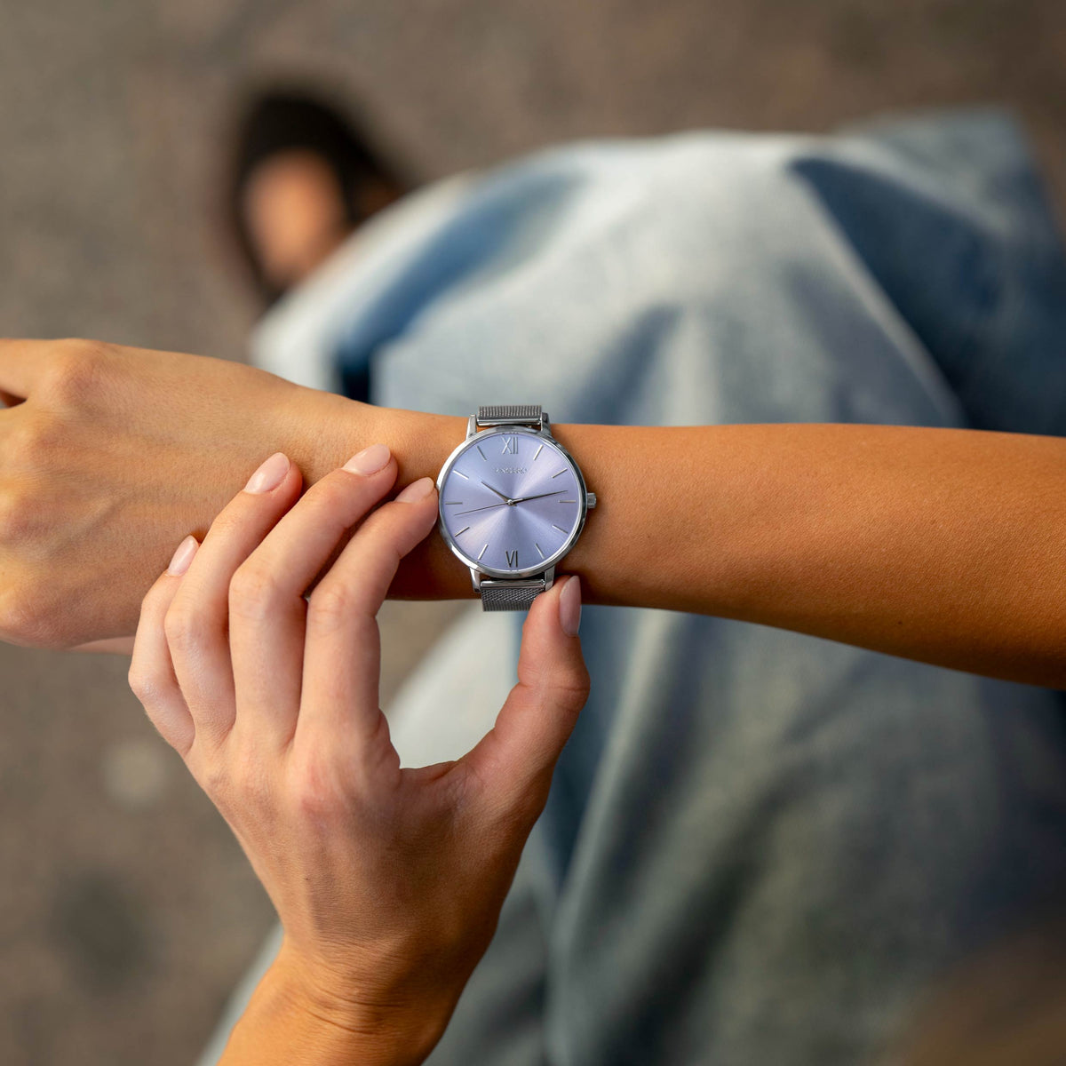 Person adjusting a watch on another person's wrist with a blurred background