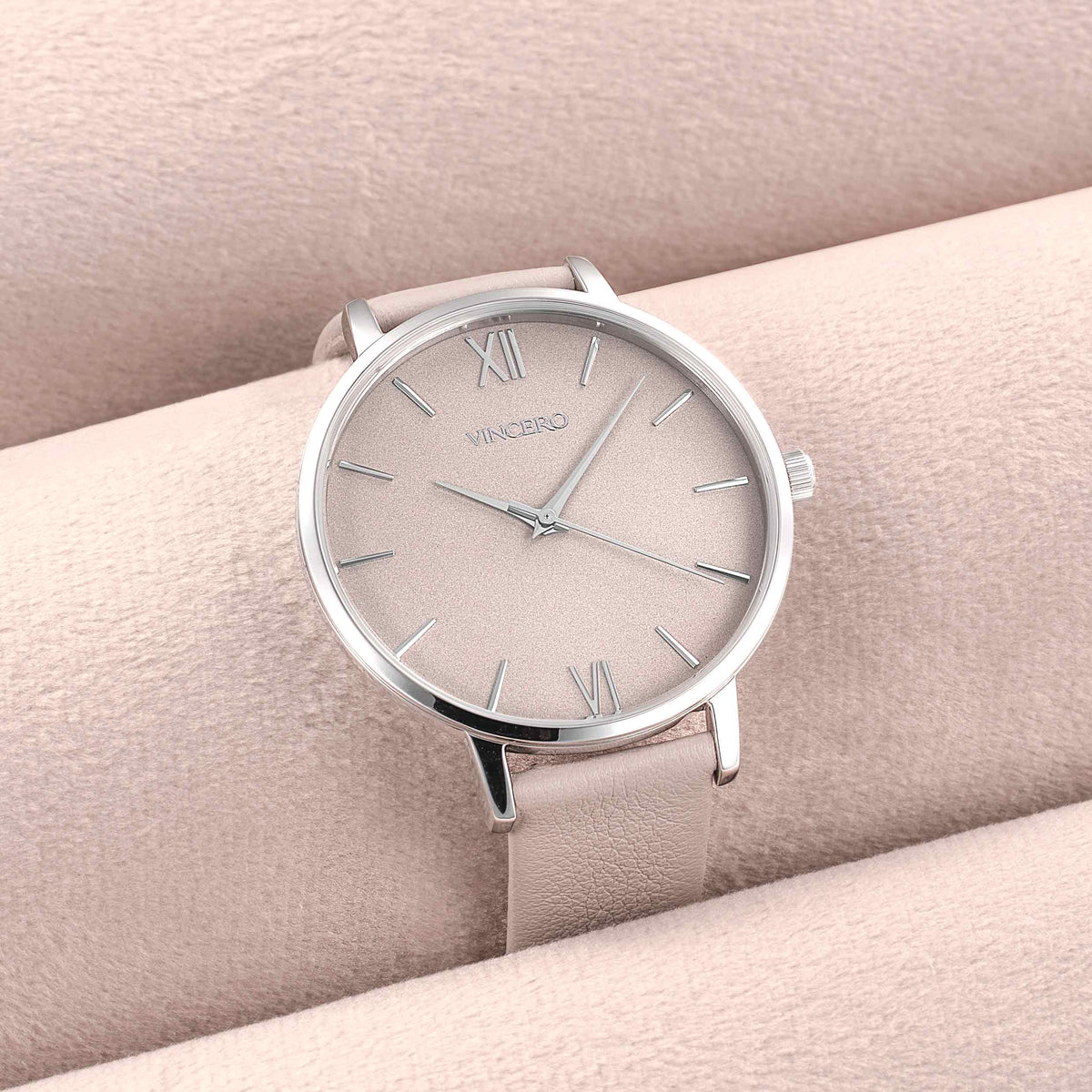 Silver watch with beige strap on a matching background