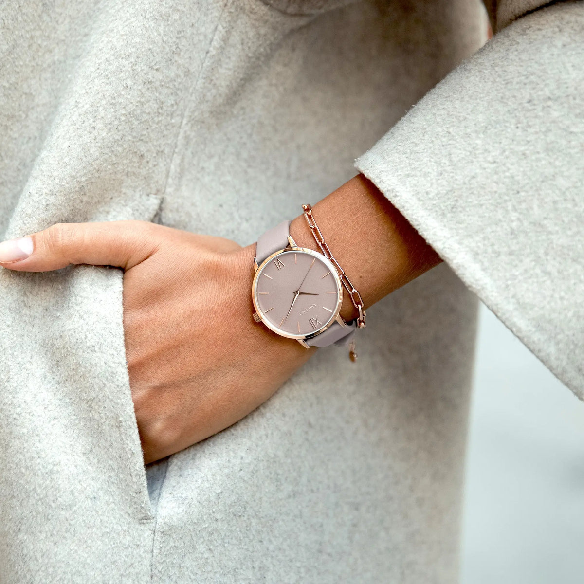 Rose gold watch on a wrist with a light gray coat