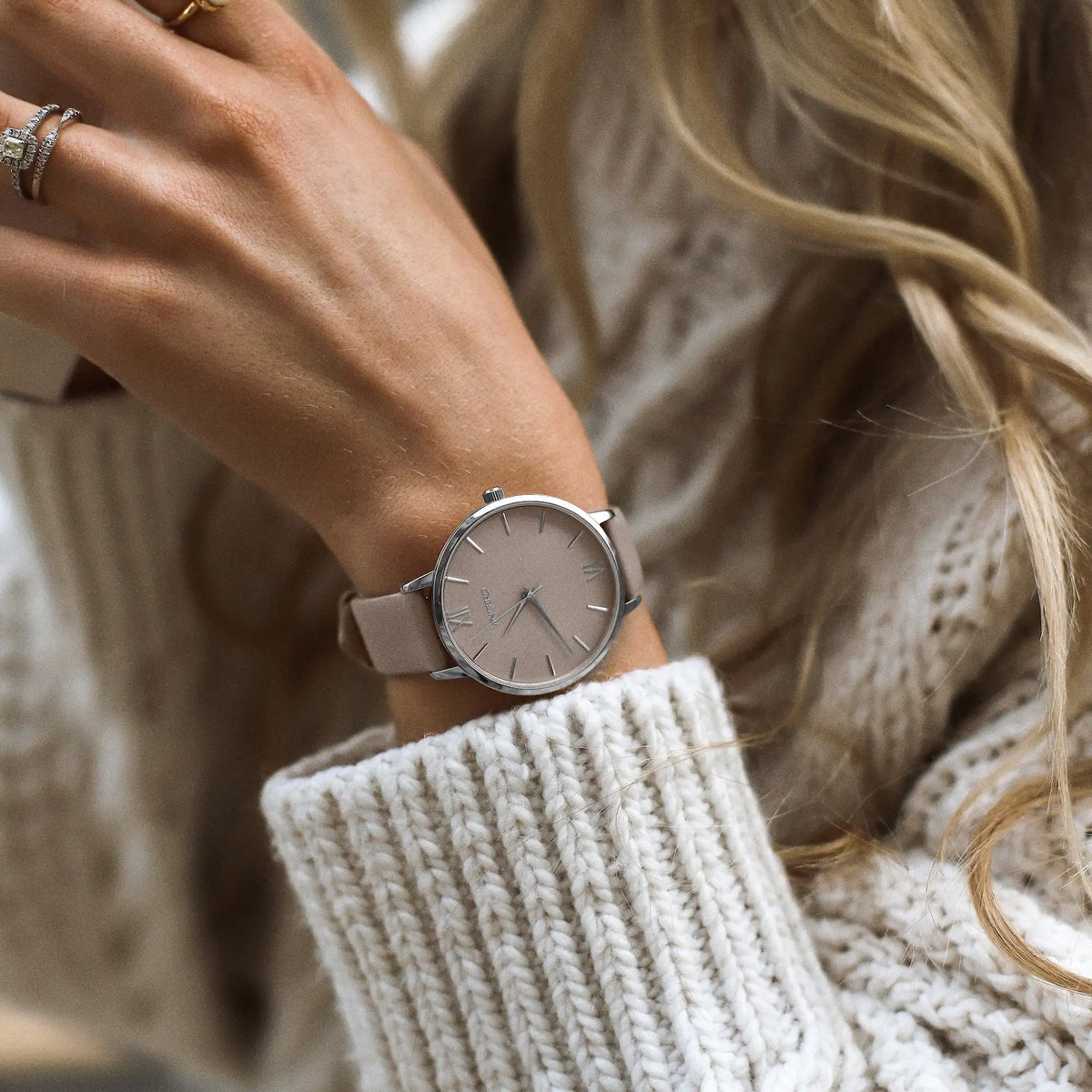 Close-up of a person wearing a watch with a neutral background