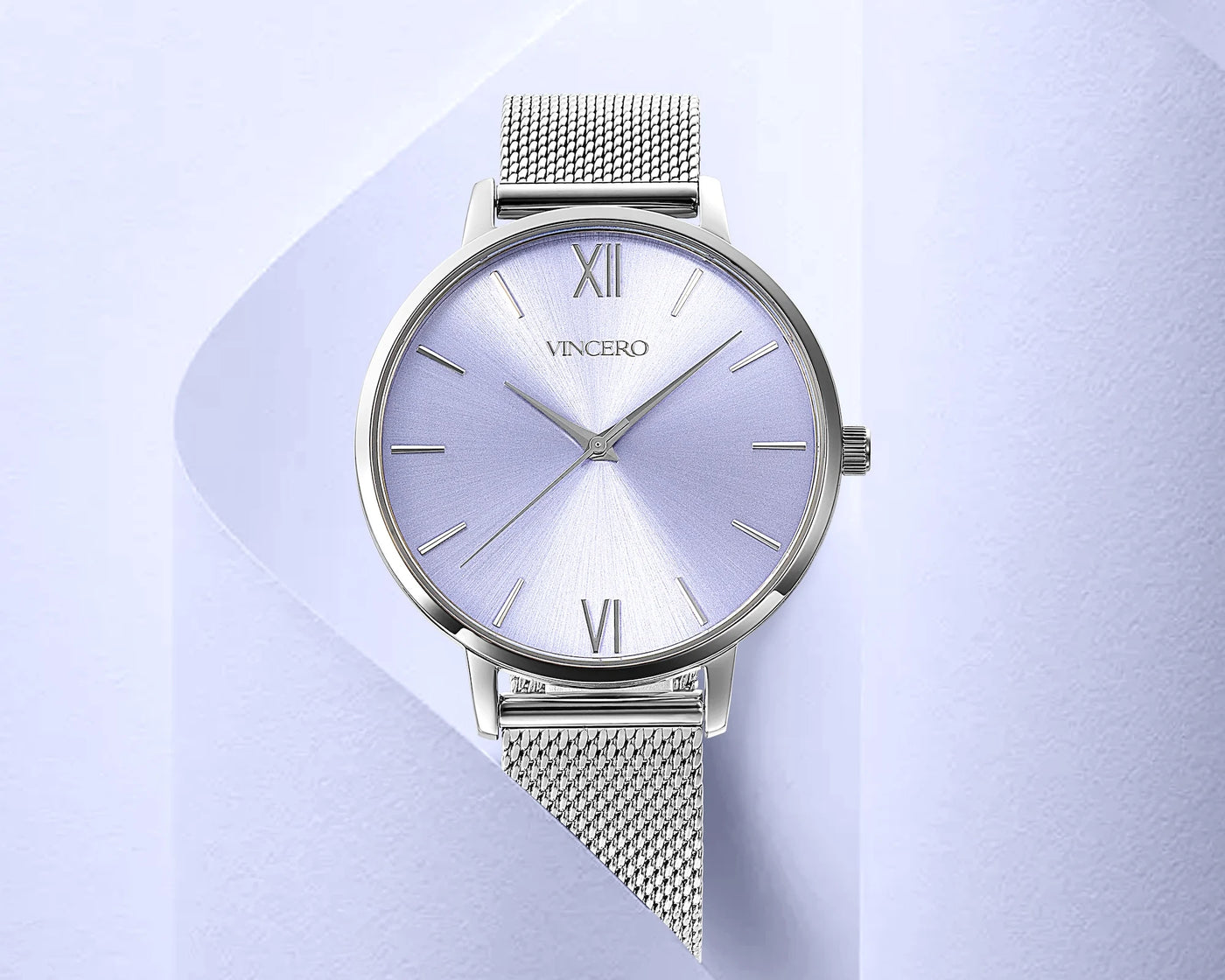 Silver wristwatch with mesh band on a light purple background