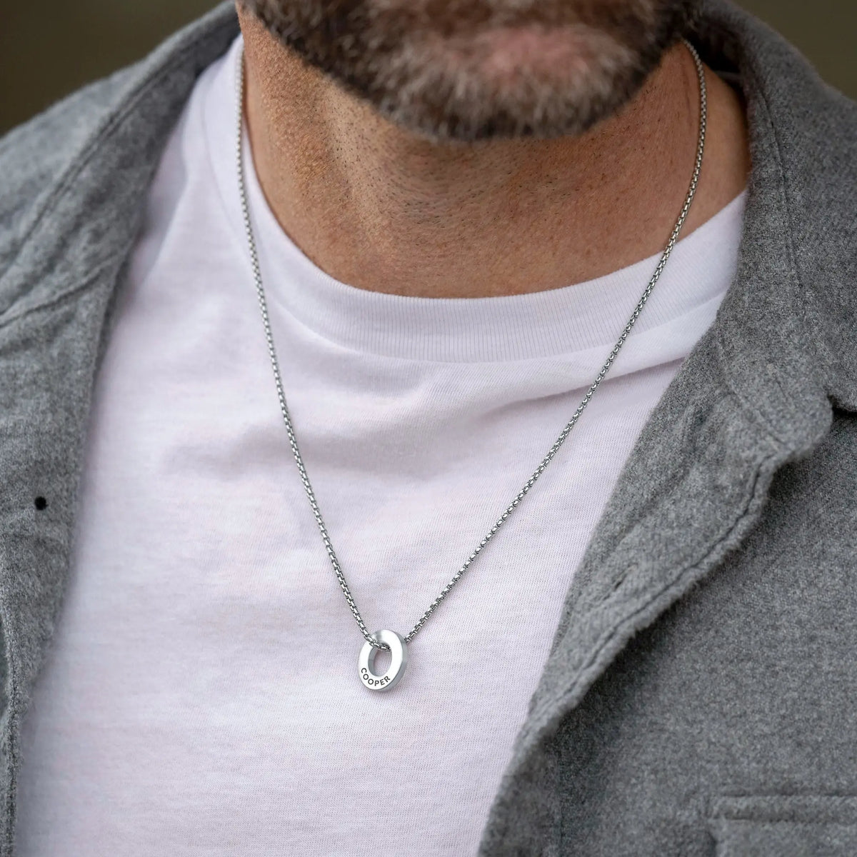 Man wearing a silver necklace with a horseshoe pendant.