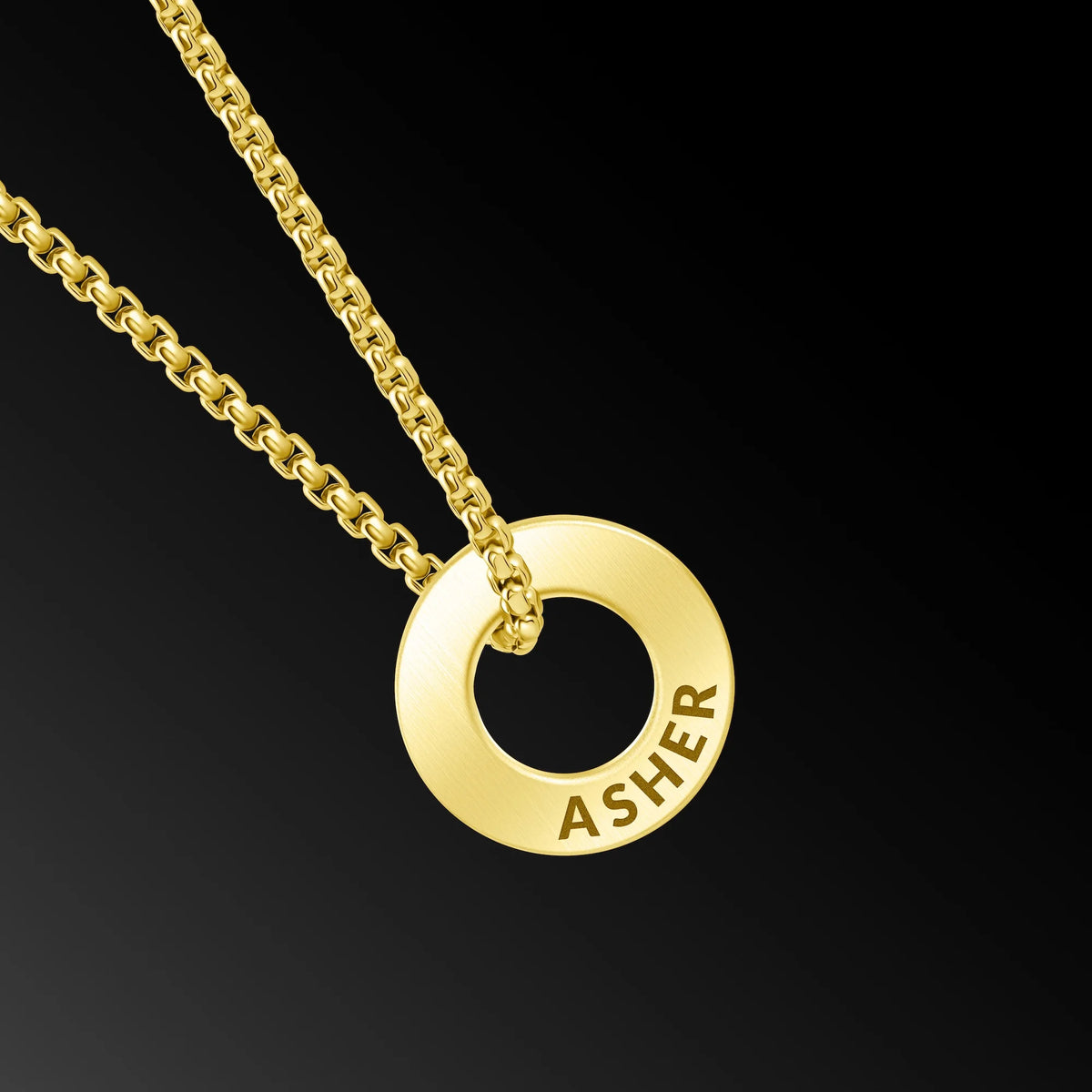A gold chain necklace with a circular ring pendant engraved with the name 'ASHER', shown against a solid black background.