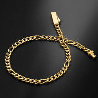 A gold-tone Cuban link chain bracelet with a rectangular tag clasp and a small cross-shaped connector, displayed on a dark textured background.