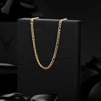 A gold-toned chain necklace draped over a black presentation box, with the brand name VINCERO subtly visible on the front. The scene is styled with black satin ribbons against a dark, moody background.