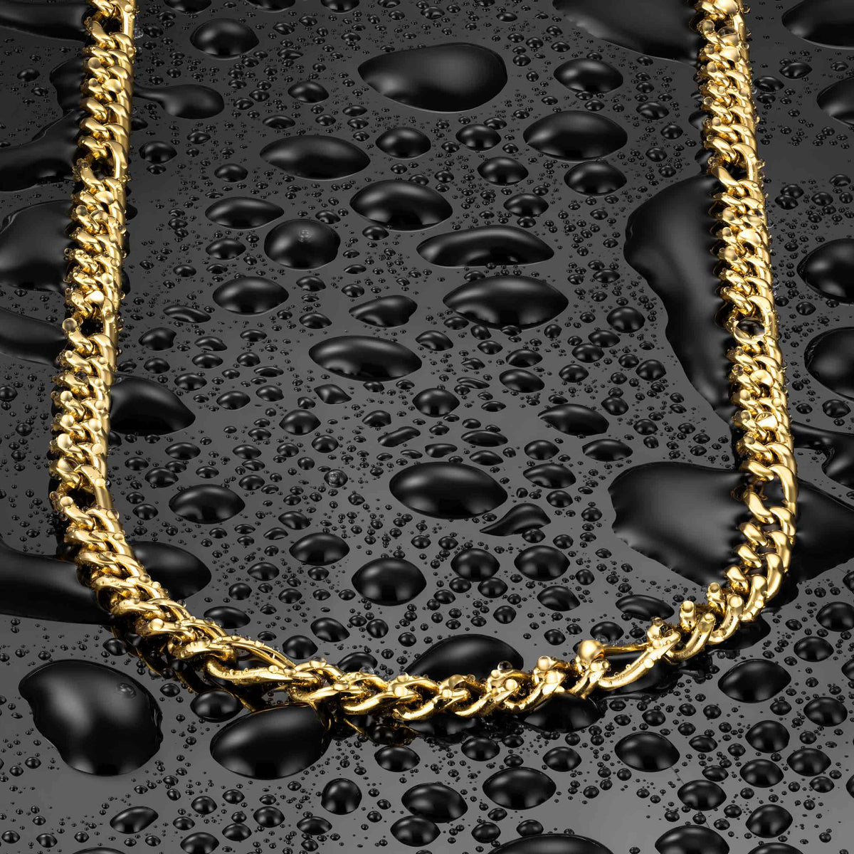 A gold-toned curb chain necklace arranged in an oval on a glossy black surface covered with water droplets.