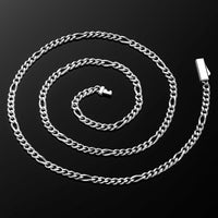 A silver Figaro chain necklace coiled in a spiral on a dark black reflective background, showing the polished metal links and clasp.