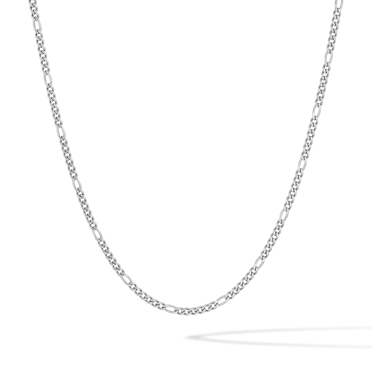 A silver Figaro chain necklace, featuring alternating elongated oval links and small round links, displayed in a curved U-shape against a clean white background.