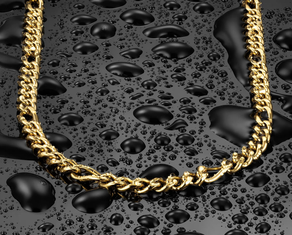 A close-up of a gold chain necklace arranged in an oval shape on a glossy black surface covered with water droplets.