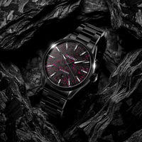 Black wristwatch with red accents on a dark textured background
