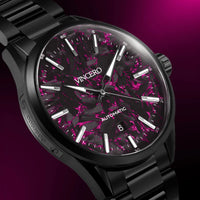 Black wristwatch with a pink and black speckled face on a purple background