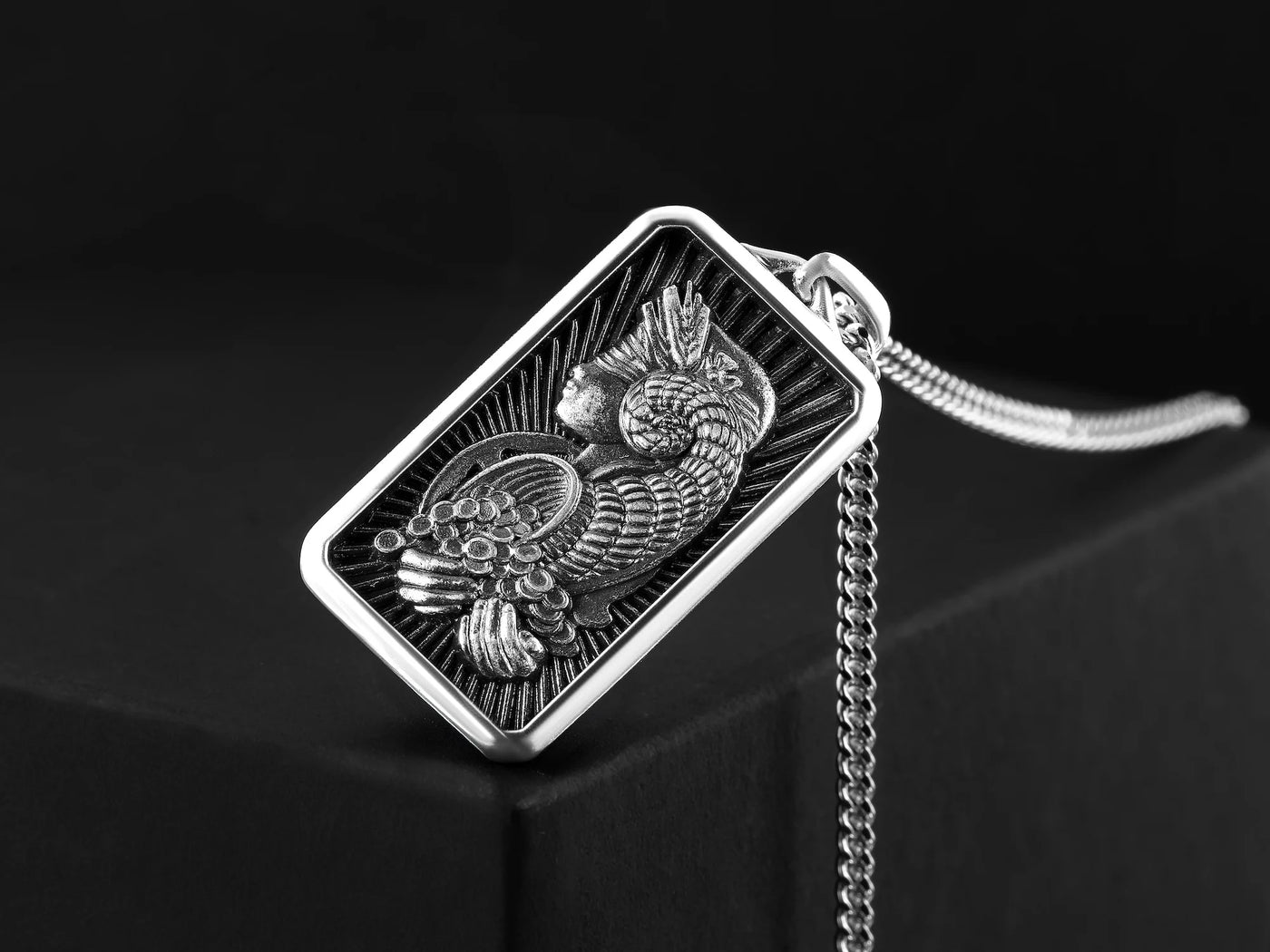 Silver pendant with intricate design on a black background