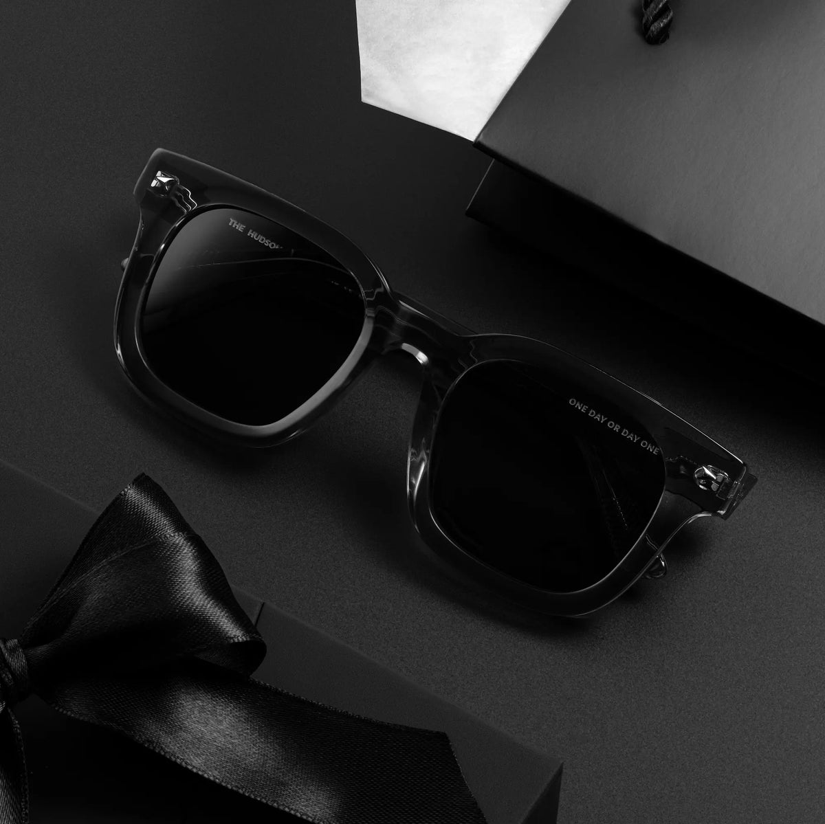 Black sunglasses and bow tie on a dark surface