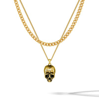Gold chain necklace with a skull pendant on a white background