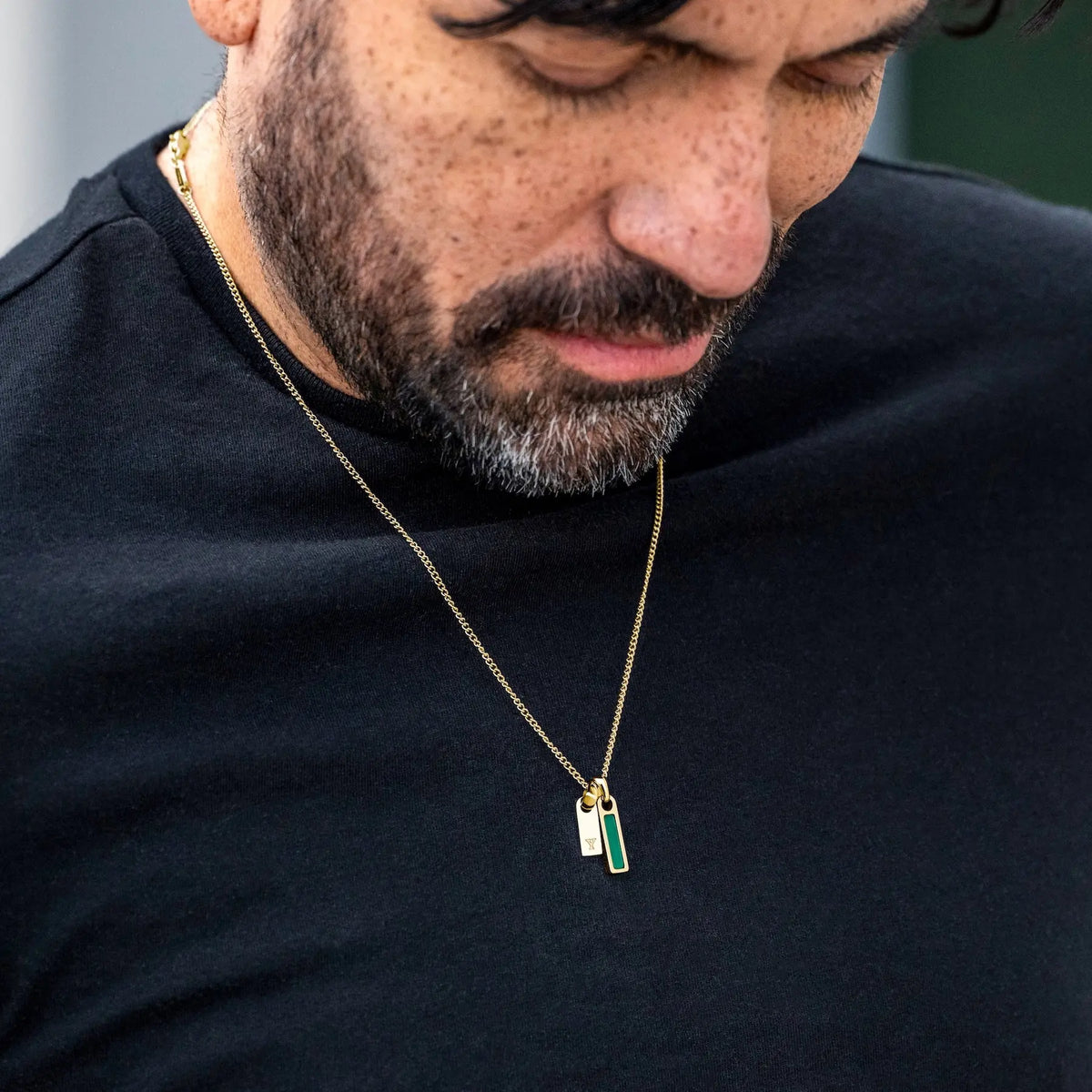 Man wearing a gold necklace with a pendant on a black background