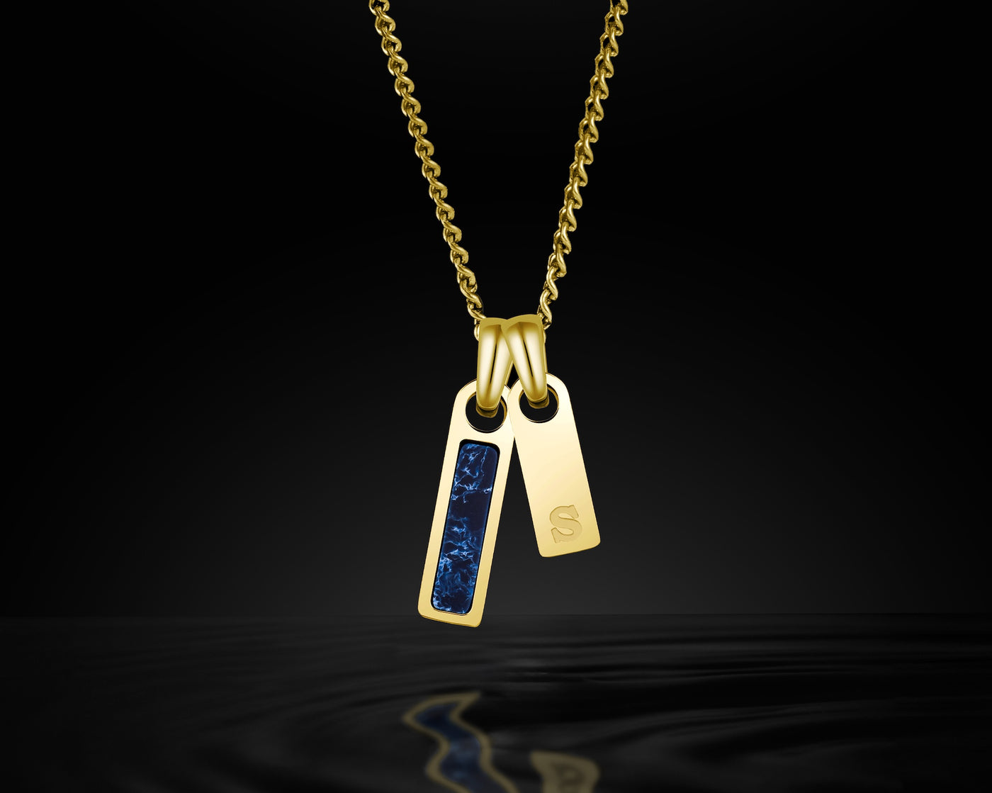 Gold necklace with two pendants, one featuring blue stones, on a black background.