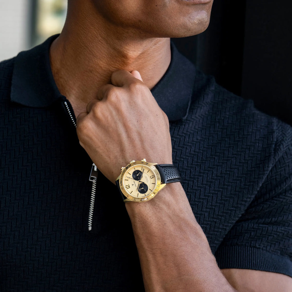 Person wearing a gold watch on a black background