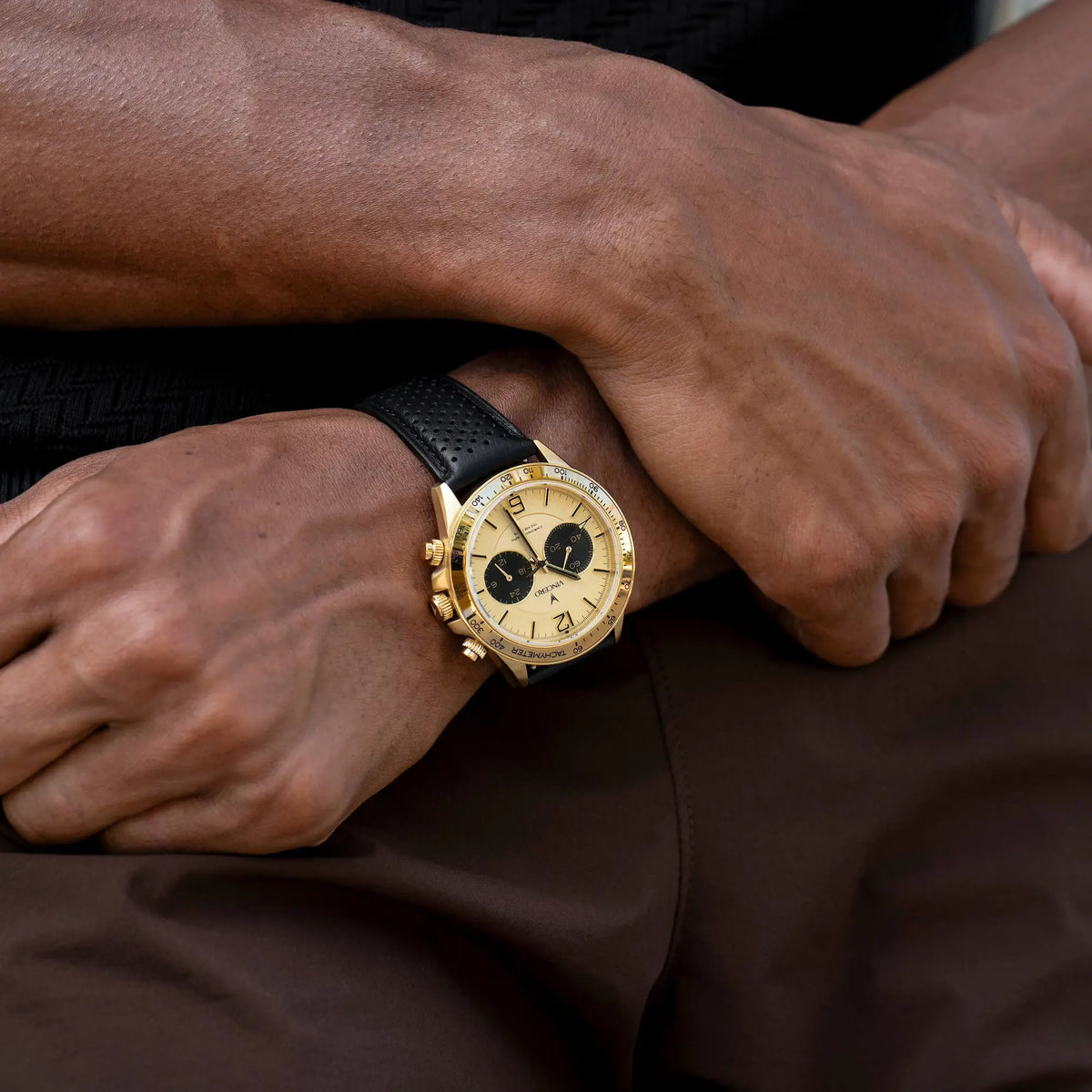 Gold watch on a wrist with a dark background