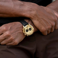 Gold watch on a wrist with a dark background