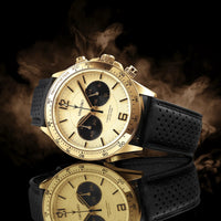 Luxury watch with gold face and black strap on a dark background