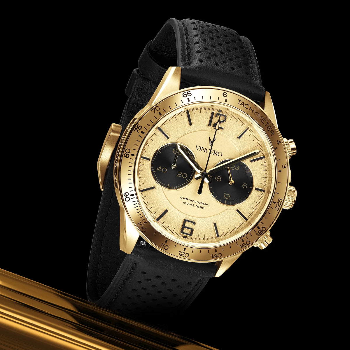 Gold wristwatch with black strap on a reflective surface