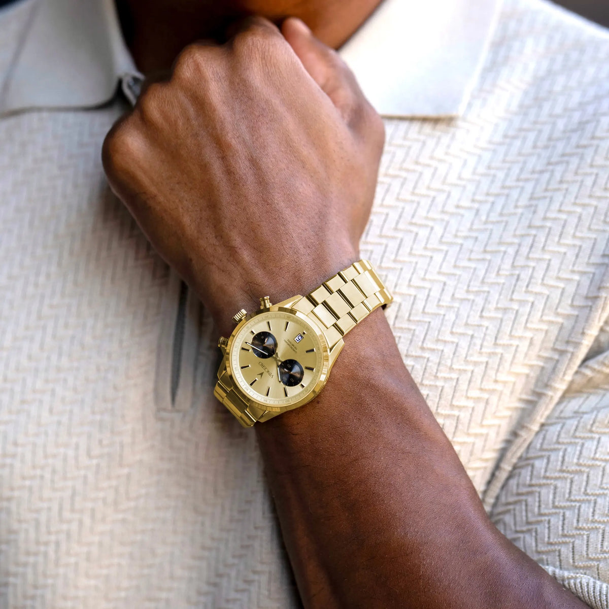 Gold wristwatch on a person's wrist with a neutral background
