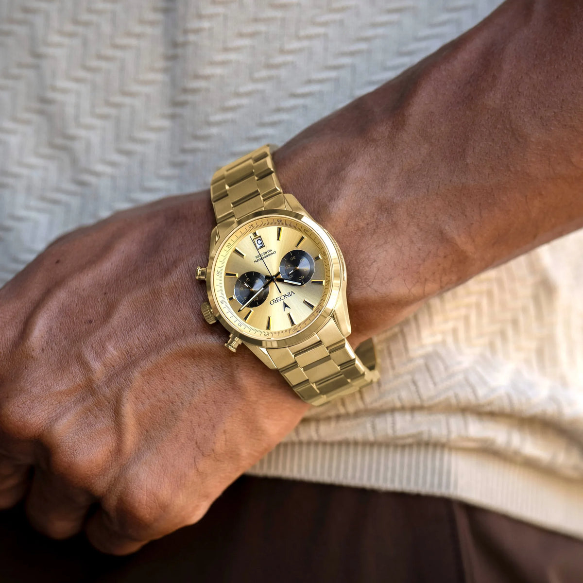 Gold wristwatch on a wrist with a neutral background