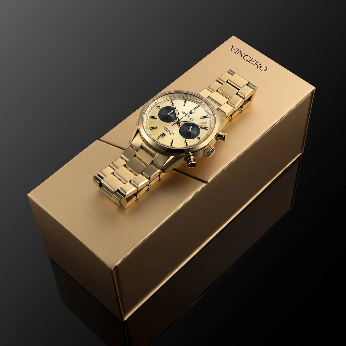 Gold wristwatch on a matching brown box with 'Vincero' branding against a dark background